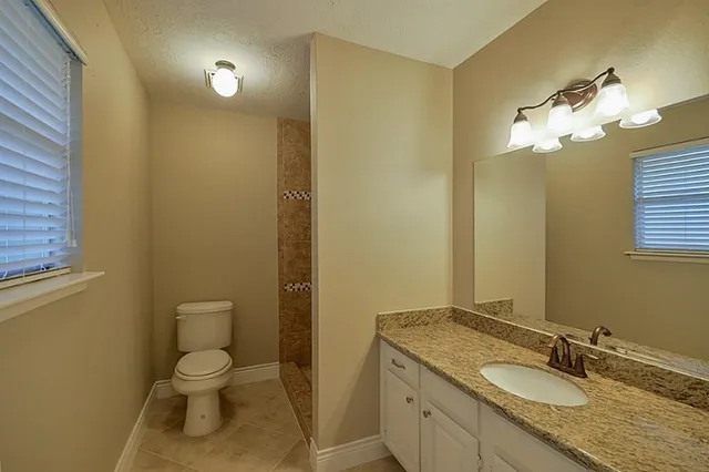a bathroom with a granite countertop toilet sink and mirror