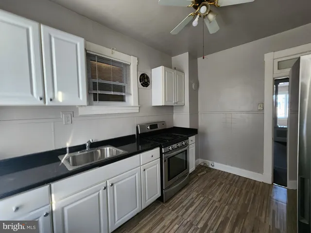 a kitchen with granite countertop a sink a stove and cabinets