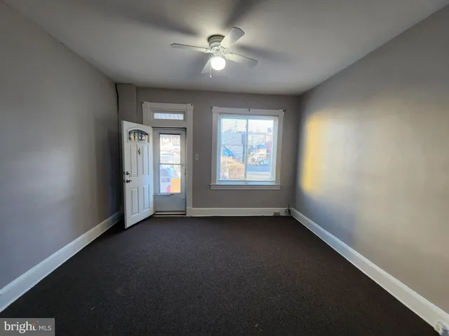 an empty room with windows and fan