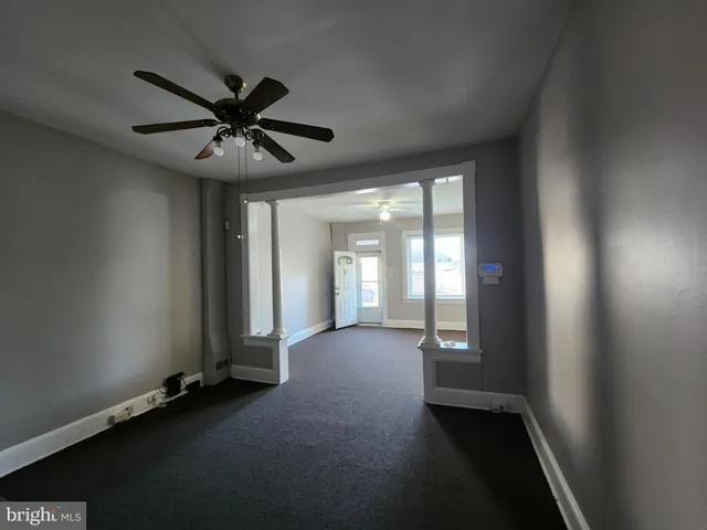 an empty room with chandelier fan and windows