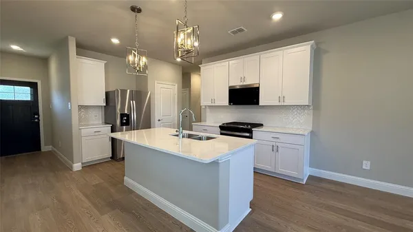 a large kitchen with stainless steel appliances a stove top oven a refrigerator a sink and a fireplace