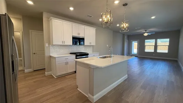 a kitchen that has a lot of white cabinets and stainless steel appliances