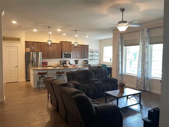 a living room with stainless steel appliances kitchen island granite countertop furniture and a large window