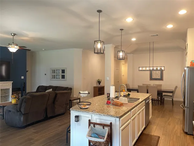 a living room with couches and kitchen view with wooden floor