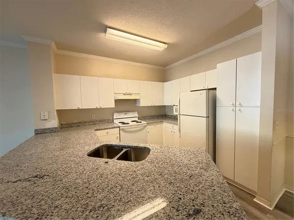 a kitchen with kitchen island a counter top a refrigerator and a sink