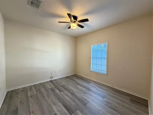 an empty room with a window and ceiling fan