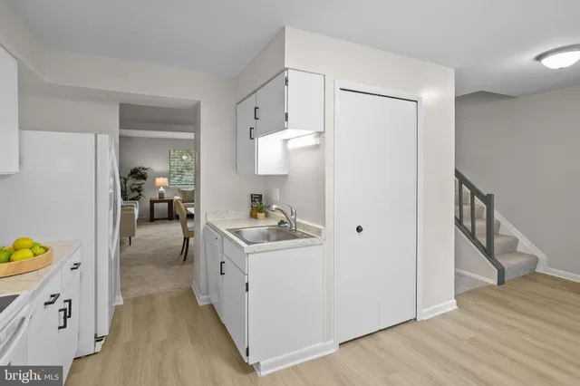 a kitchen with a sink a stove cabinets and wooden floor