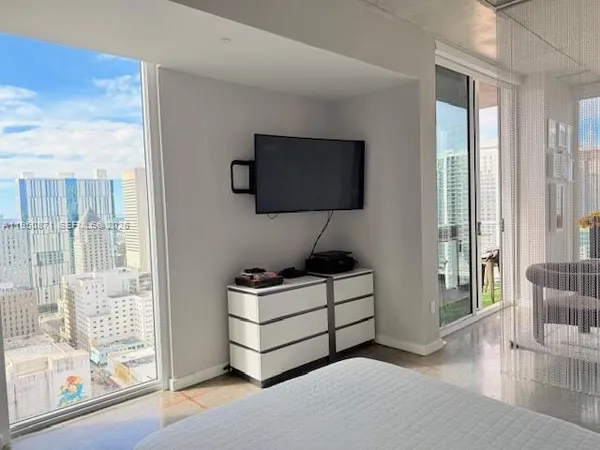 a living room with furniture a flat screen tv and floor to ceiling window