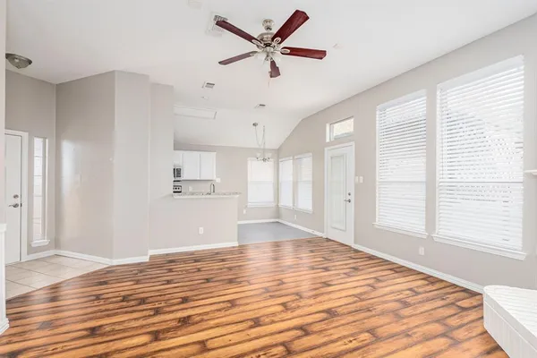 a view of empty room with wooden floor and fan