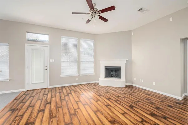 a view of empty room with wooden floor and fan
