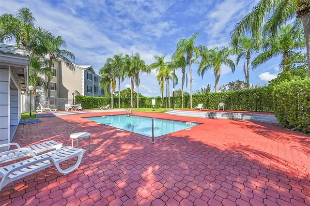 a view of pool with lawn chairs and wooden fence