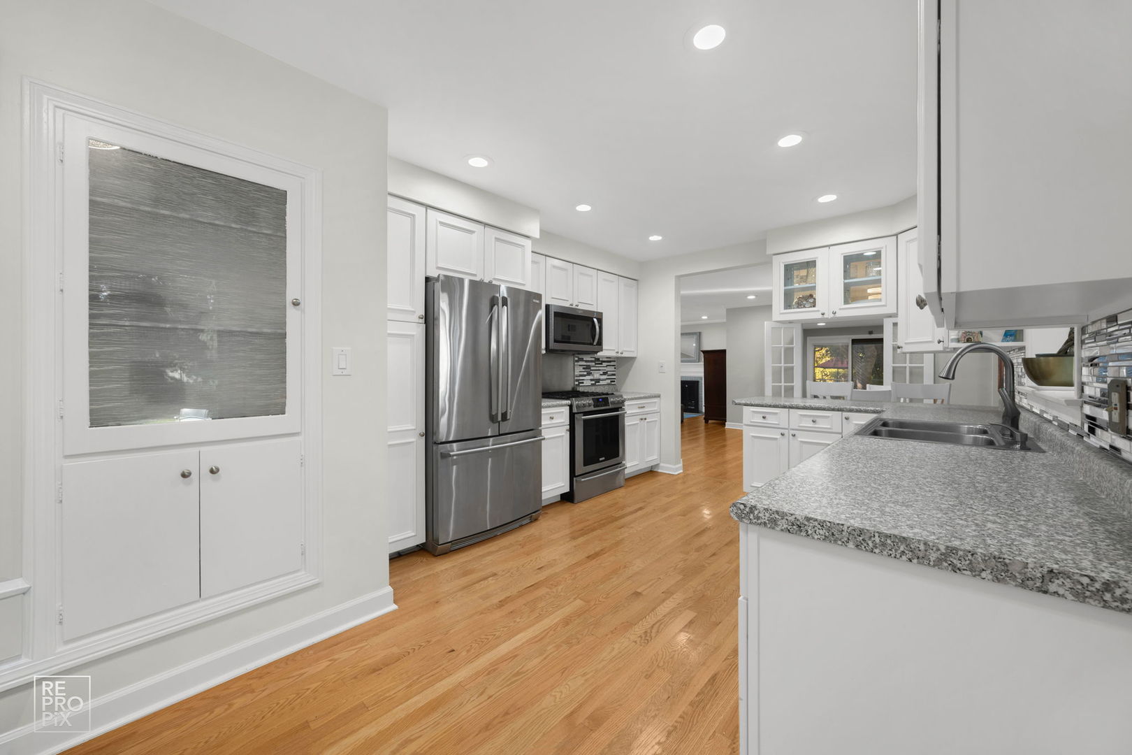 6872 North Loron Avenue Chicago, IL 60646 - Photo 19 of 25 a kitchen with stainless steel appliances granite countertop a refrigerator a stove and a sink with wooden floors