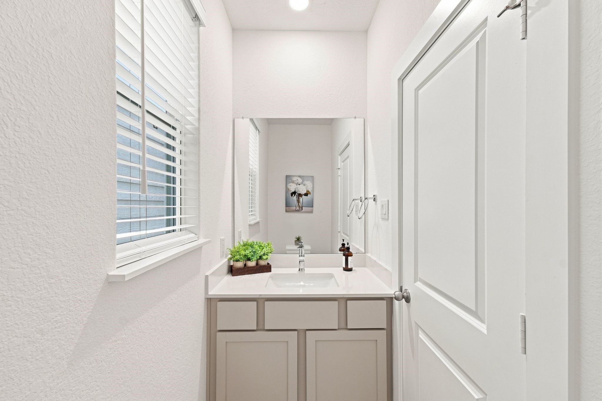 6063 Cebra Street Houston, TX 77091 - Photo 37 of 50 Bright and stylish powder room featuring a modern vanity, quartz countertop, large mirror, and natural light. Photos are from a different property with the same floor plan, features, and finishes. **Orientation may vary.**