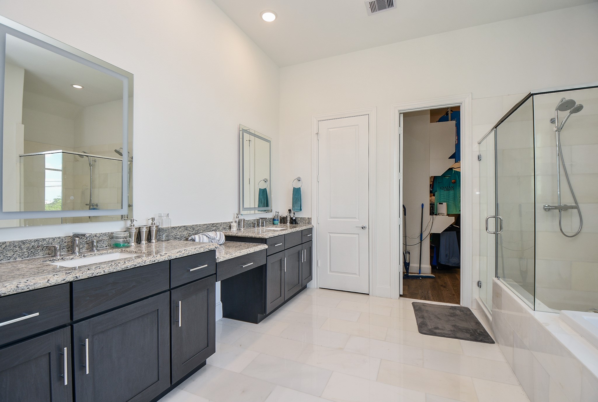 703 Bringhurst Street Houston, TX 77020 - Photo 17 of 27 This is a modern bathroom featuring
a sleek vanity with a dark countertop,
under-mount double sinks, and contemporary
faucet. It has a large mirror and a separate tub, soaking with light-colored tile, creating a clean and bright space.