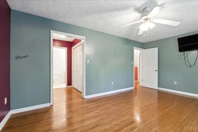 a view of an empty room with window and wooden floor