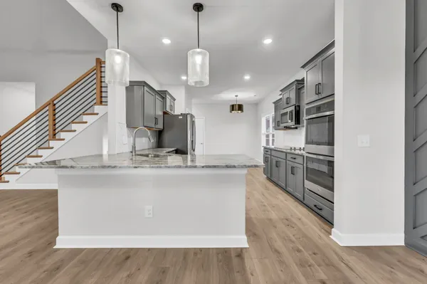 a kitchen with stainless steel appliances granite countertop a sink a stove and a wooden floors
