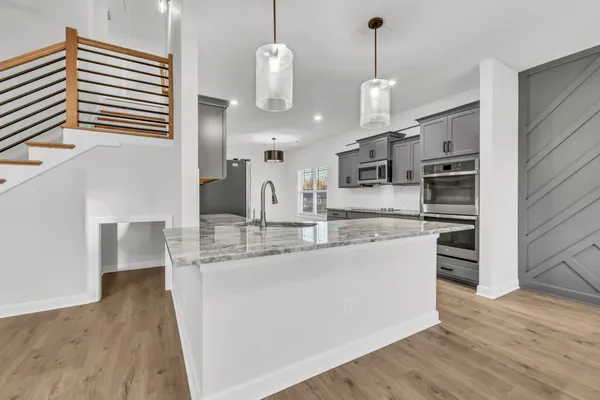 a kitchen with stainless steel appliances granite countertop a sink a stove and a wooden floors