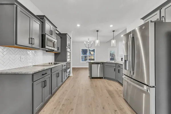 a kitchen with stainless steel appliances granite countertop a refrigerator a stove and a sink