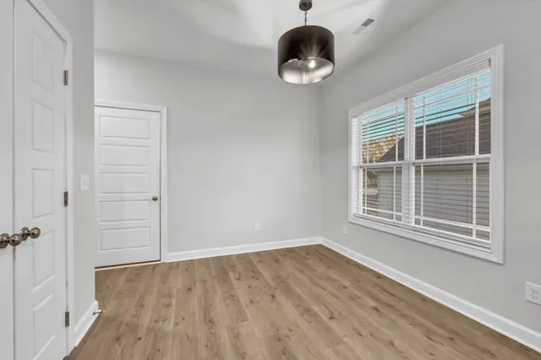 a view of an empty room with a window and wooden floor