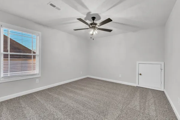 an empty room with a window and a fan