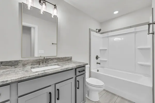 a bathroom with a granite countertop toilet sink and mirror