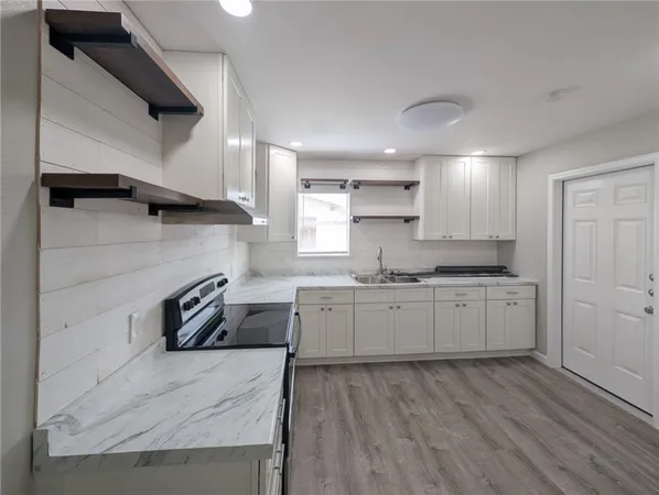 a kitchen with granite countertop a sink a stove and cabinets