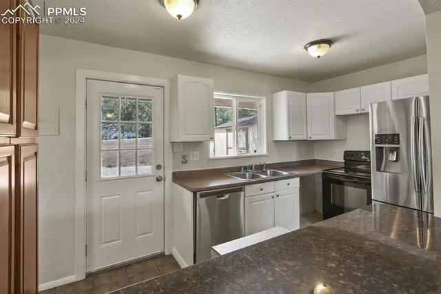 a kitchen with granite countertop a refrigerator and a stove top oven