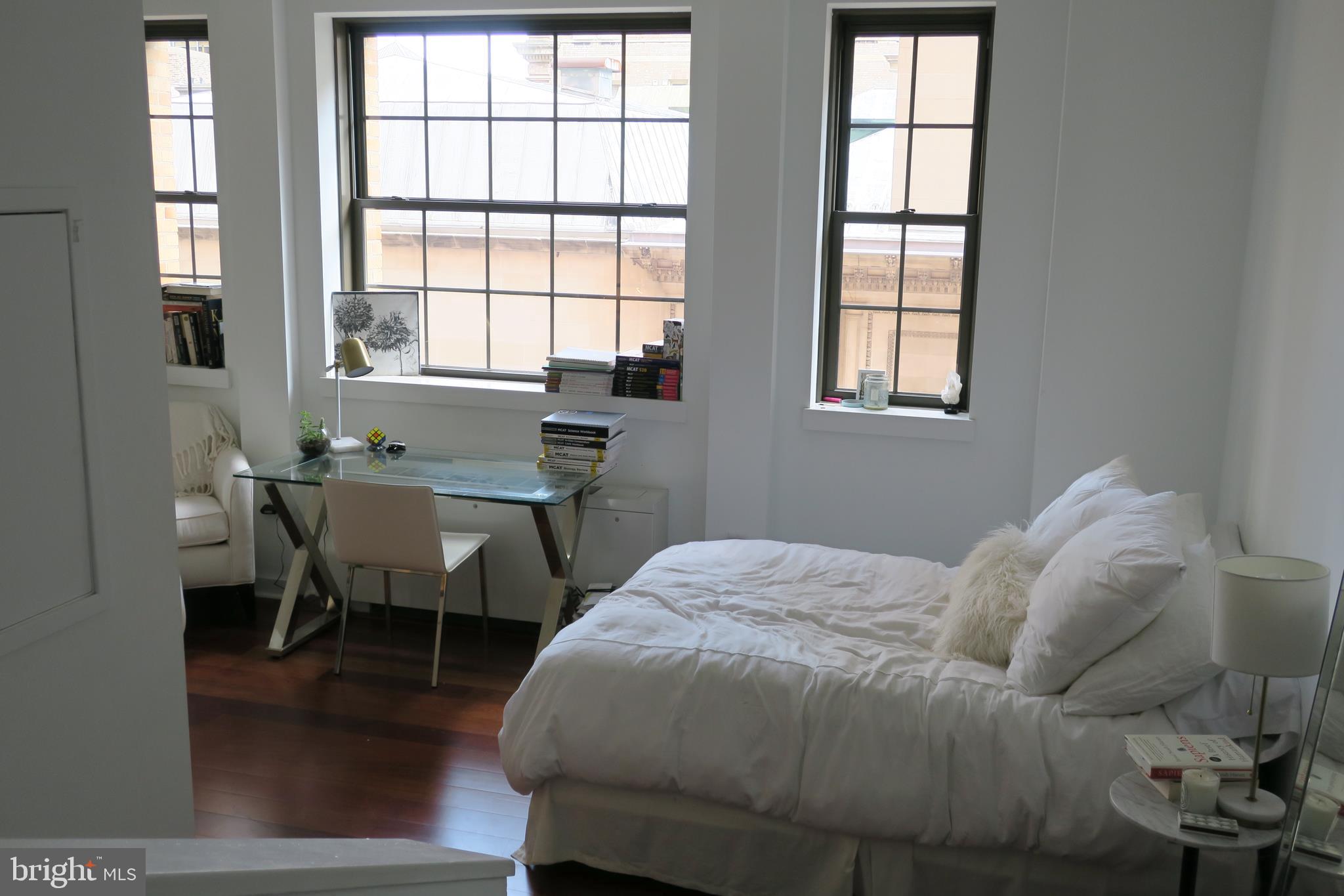 a bedroom that has a bed and a table in it with window