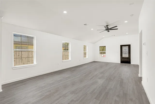 a view of an empty room with a window and wooden floor