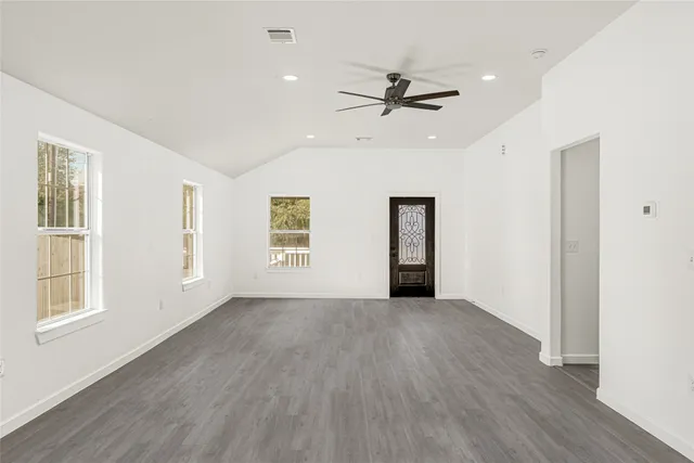an empty room with wooden floor closet and windows