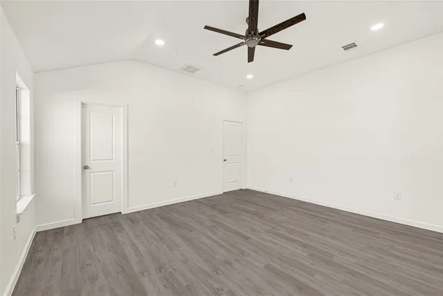an empty room with wooden floor and windows