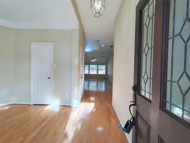 a view of a hallway with wooden floor and a livingroom
