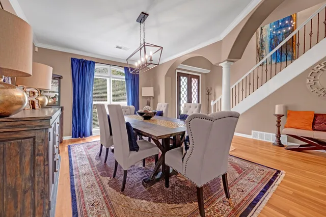 a dining room with wooden floor a chandelier a wooden table and chairs