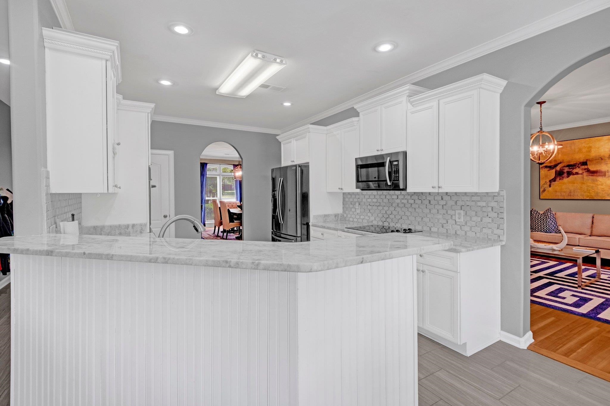 546 Township Cove Collierville, TN 38017 - Photo 8 of 40 Kitchen featuring stainless steel microwave, freestanding refrigerator, arched walkways, tasteful backsplash, and recessed lighting