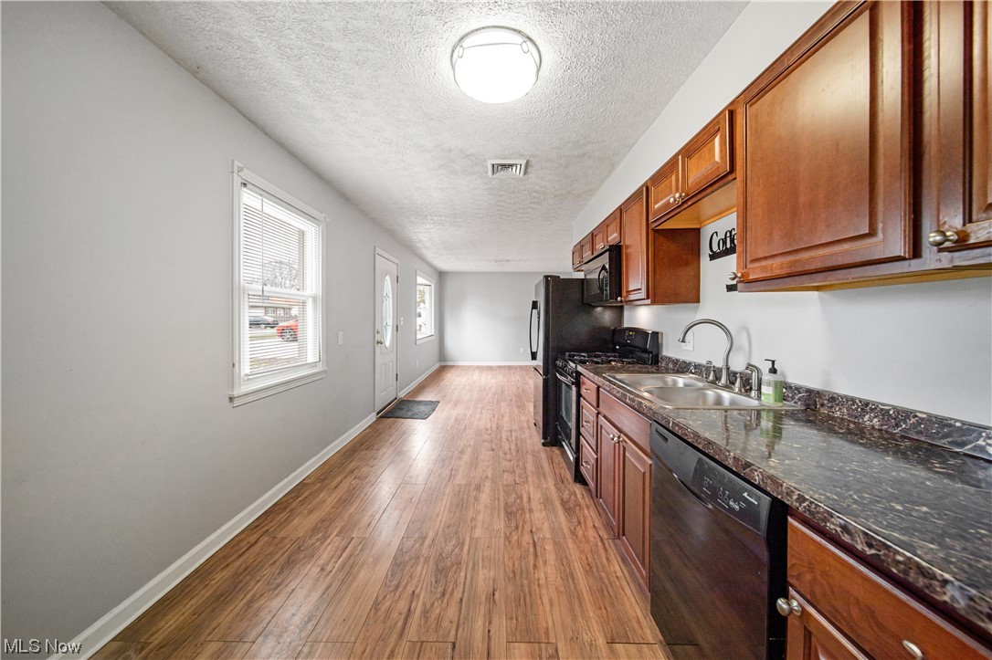 4887 Orchard Road Mentor, OH 44060 - Photo 13 of 26 Kitchen with black appliances, sink, a textured ceiling, and wood-type flooring