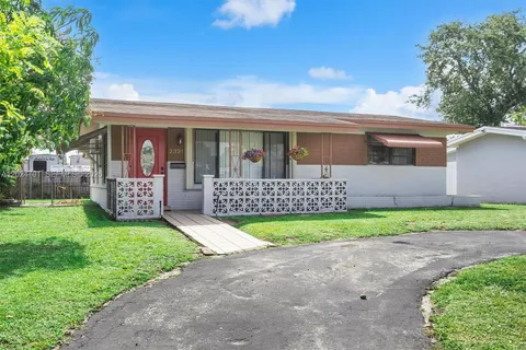 a view of a house with a yard and a large tree
