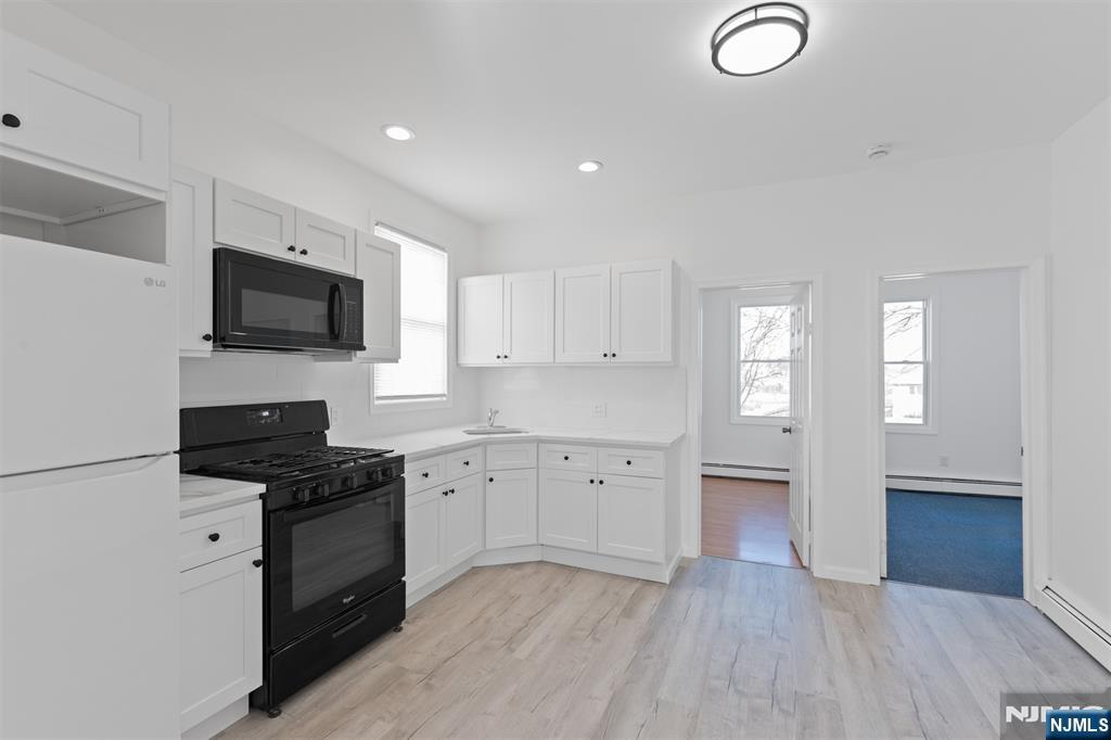 118 Ray Street, Unit 2 Garfield, NJ 07026 - Photo 6 of 15 a kitchen with granite countertop a stove top oven sink and cabinets
