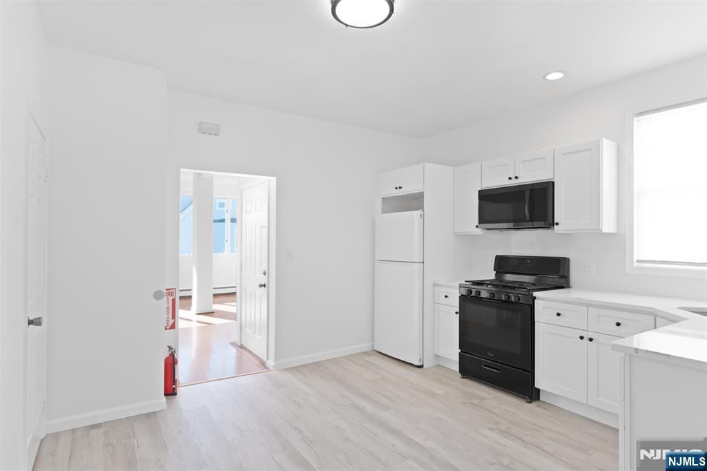 118 Ray Street, Unit 2 Garfield, NJ 07026 - Photo 8 of 15 a view of a kitchen with a sink wooden floor and a refrigerator