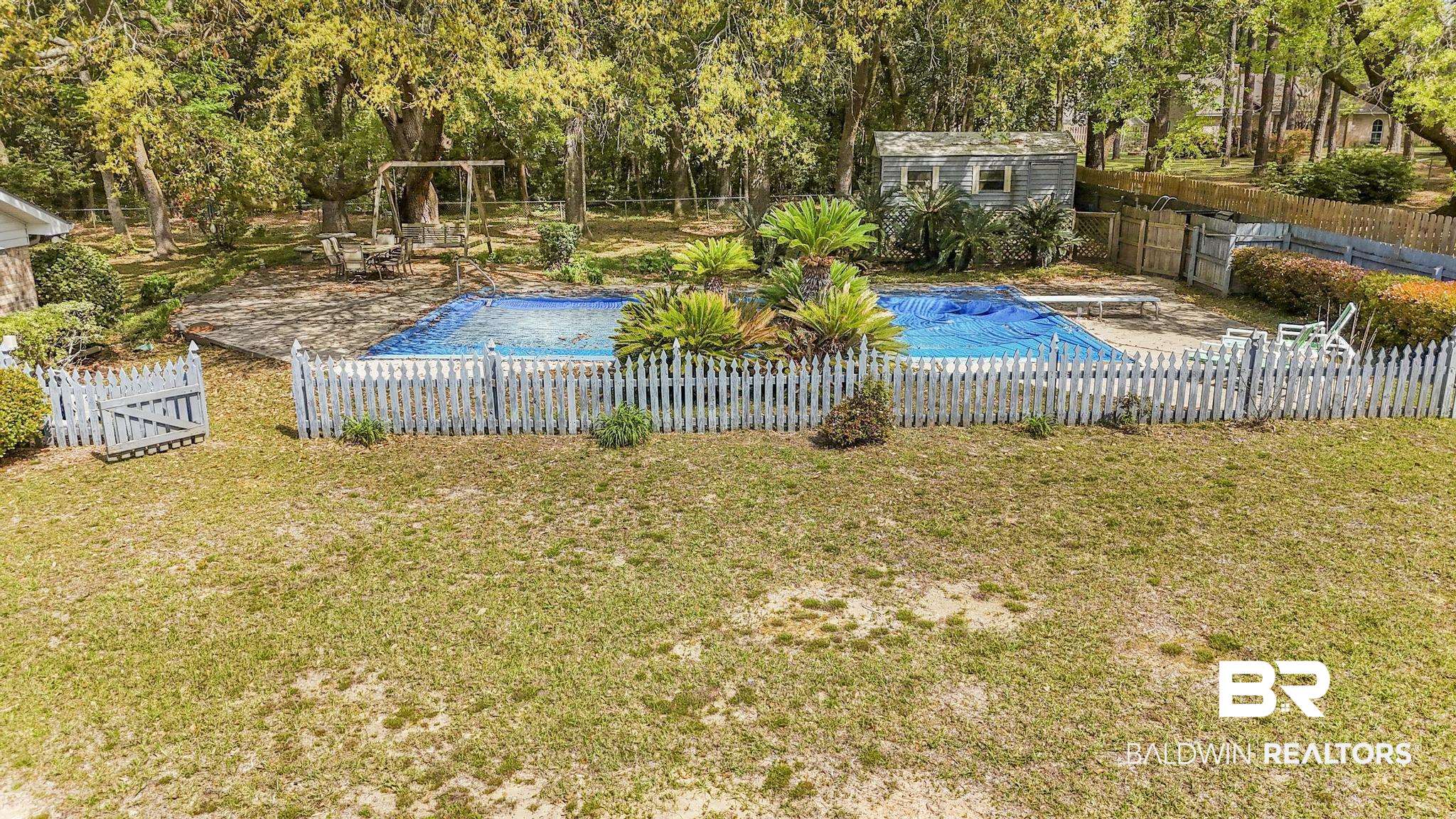 10207 Plantation Drive Daphne, AL 36526 - Photo 18 of 48 View of swimming pool with patio surround, a fenced backyard, view of scattered trees, and an outdoor structure