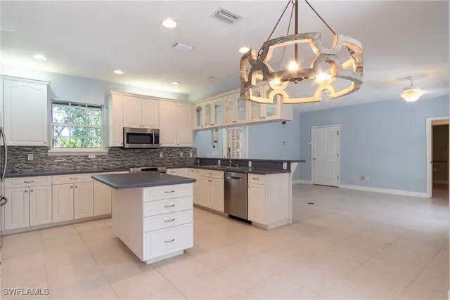 a kitchen with cabinets appliances and a chandelier