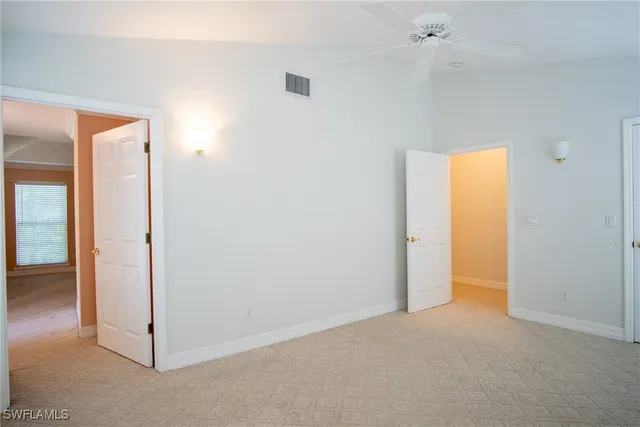 an empty room with windows and fan