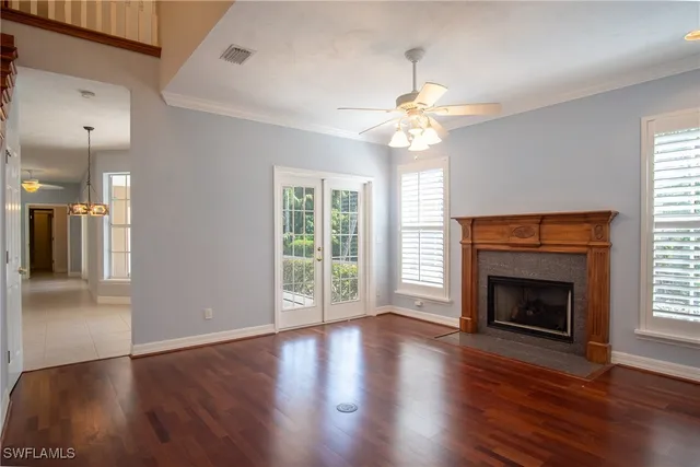 an empty room with wooden floor fireplace cabinet and windows