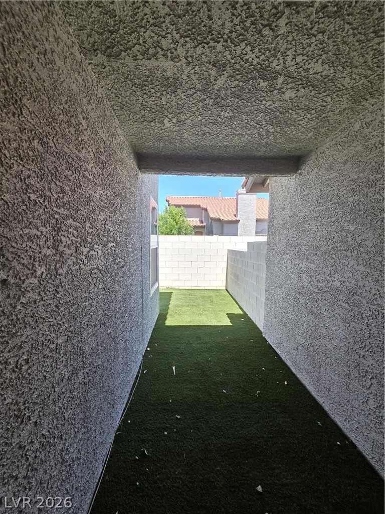 2275 Ramsgate Drive Henderson, NV 89074 - Photo 18 of 84 An enclosed outdoor area features textured walls and a mix of paved and green surfaces.