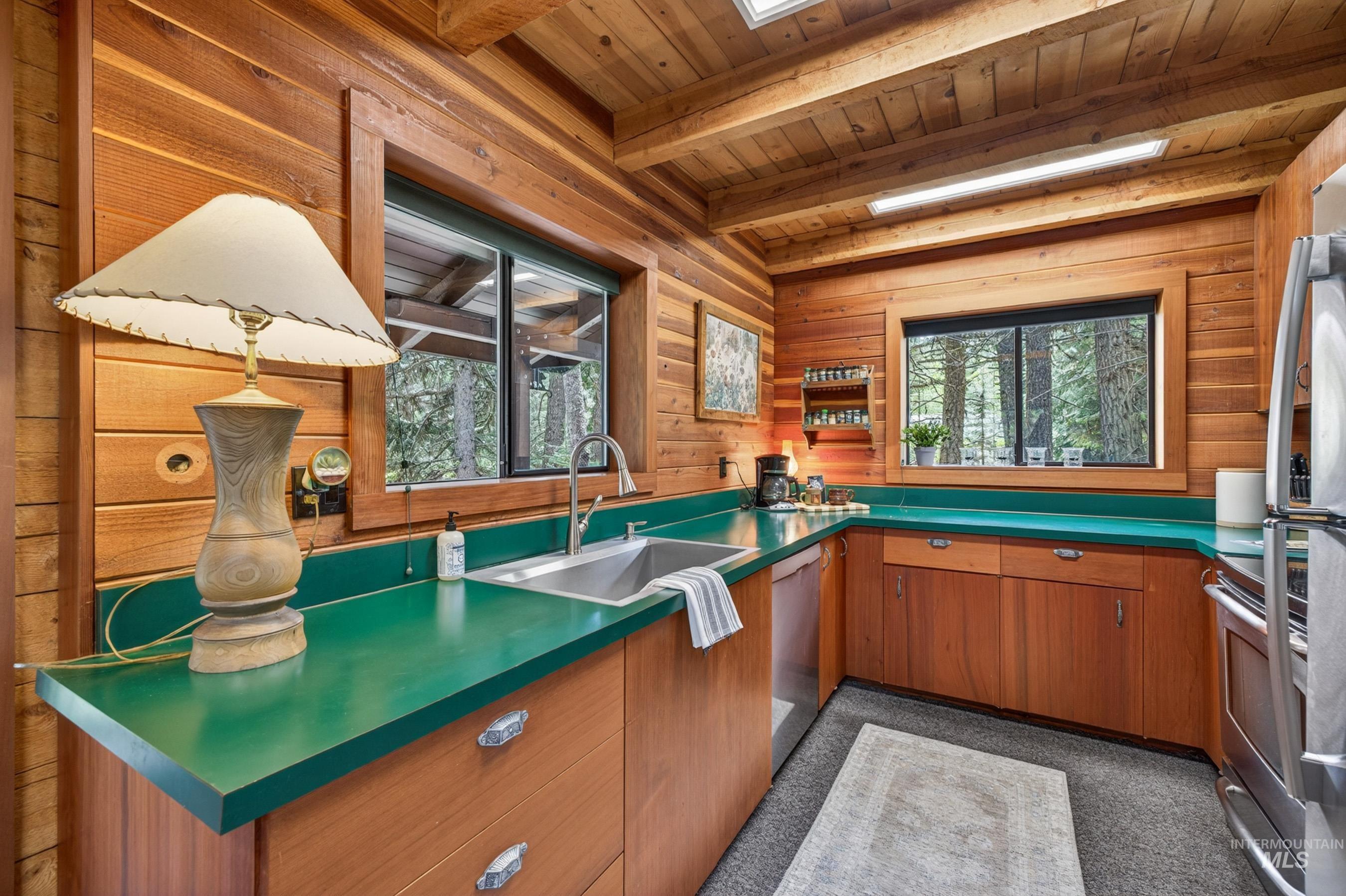 2339 West Mountain Road Donnelly, ID 83615 - Photo 6 of 37 Wood-paneled kitchen featuring solid wood cabinetry, green countertops, stainless steel appliances, and a stainless steel sink with a gooseneck faucet