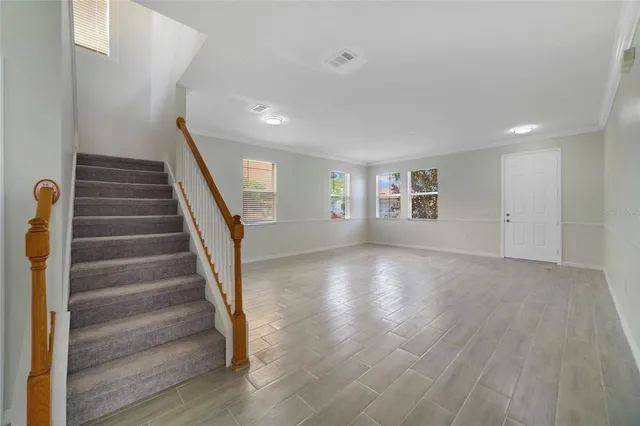 a view of an empty room with wooden floor and stairs