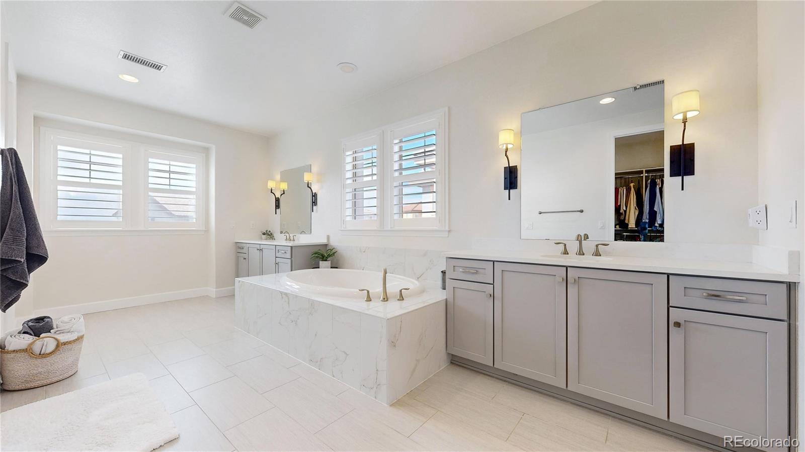 1476 Red Sun Way Highlands Ranch, CO 80126 - Photo 21 of 37 a spacious bathroom with a double vanity sink a mirror and a bathtub