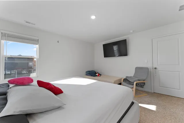 a bedroom with a bed a flat screen tv and a potted plant