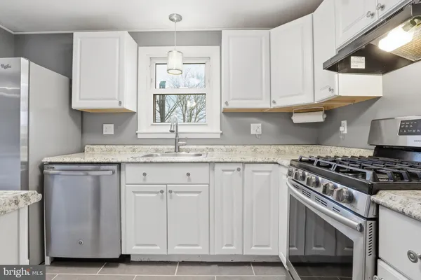 a kitchen with granite countertop white cabinets and stainless steel appliances