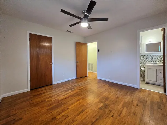 an empty room with wooden floor and a ceiling fan