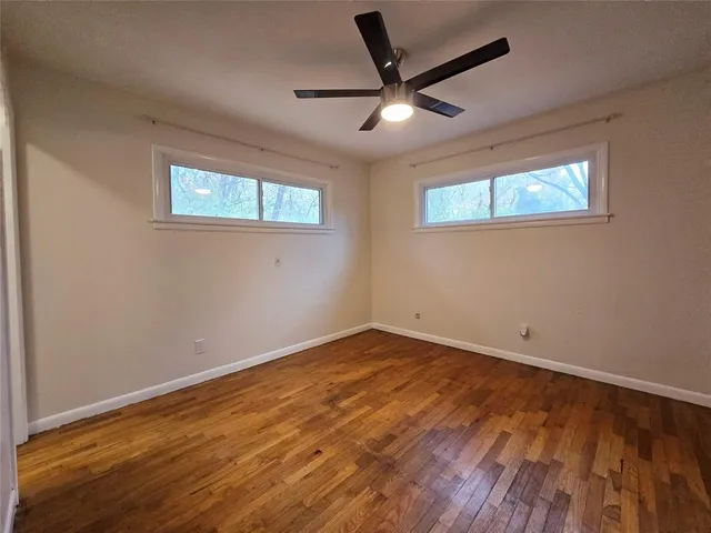 an empty room with wooden floor and ceiling fan
